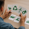 Persona observando cartas con símbolos de energía solar, reciclaje, agricultura y finanzas sostenibles, representando decisiones de emprendimiento verde.